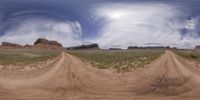 a panorama of the dirt road that leads into the sky in a desert with grass and rocks