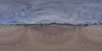 a panorama of a wide open desert field under stormy skies, including grey clouds and dark skies