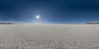 a panoramic image of the desert with a sun in the middle and sand in the foreground