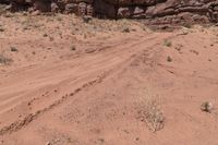 a dirt road in the desert with many rocks on a hillside near the shore of a canyon