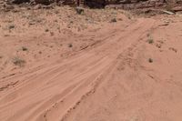 a dirt road in the desert with many rocks on a hillside near the shore of a canyon