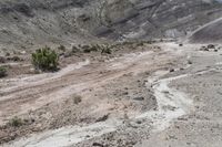 the road is dirty and dirty in the desert as it passes by some mountains