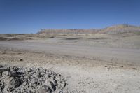 a dirt road is surrounded by some hills and desert like terrain as the vehicle sits on it