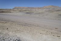 a dirt road is surrounded by some hills and desert like terrain as the vehicle sits on it