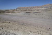 a dirt road is surrounded by some hills and desert like terrain as the vehicle sits on it