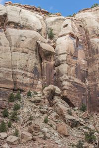 a man riding a motor bike past a big rock formation on the side of a mountain