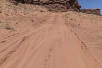 a dirt road leading up to rocks on the edge of a cliff that appears to be very dry