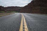 a person riding a motorcycle along a narrow road through rocks and sand cliffs a grassy area on both sides