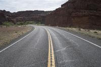 a person riding a motorcycle along a narrow road through rocks and sand cliffs a grassy area on both sides