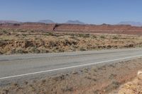 a long curved road with some rocks on both sides of it in the desert, along with hills and scrub