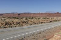 a long curved road with some rocks on both sides of it in the desert, along with hills and scrub