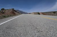 an empty highway is pictured surrounded by rocks and dry grass, during the day time