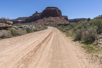 the desert road is empty and has many plants and vegetation growing on it, along with mountains in the background