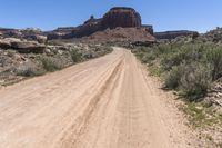 the desert road is empty and has many plants and vegetation growing on it, along with mountains in the background