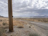 an empty road sits in a deserted area, under a cloudy sky near power lines