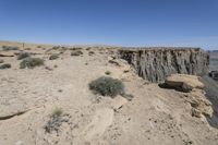 a dirt road in the middle of a desert area with a large crack in the cliff