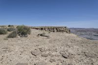 a dirt road in the middle of a desert area with a large crack in the cliff