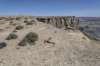 a dirt road in the middle of a desert area with a large crack in the cliff