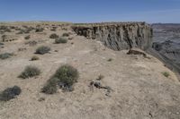 a dirt road in the middle of a desert area with a large crack in the cliff