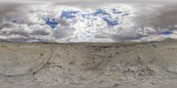 a panoramic view shows sand and cloudy skies as the snow slopes in the area