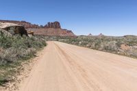 the dirt road is dirty as it goes through the desert in the daytime time with blue sky