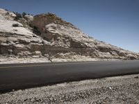 a road near mountains, with no cars on it to the left of the photo