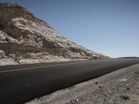 a road near mountains, with no cars on it to the left of the photo