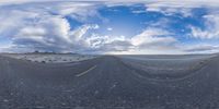 a spherical view shows the open road leading towards the sky and mountains while there is no traffic