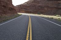 a person riding a motorcycle along a narrow road through rocks and sand cliffs a grassy area on both sides