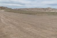 an empty field next to a big mountain with rocks in the background of the picture