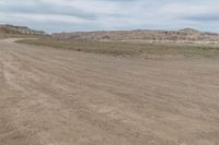 an empty field next to a big mountain with rocks in the background of the picture