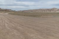 an empty field next to a big mountain with rocks in the background of the picture