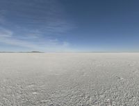 a lone person on a large ice covered field with some desert around it in the background