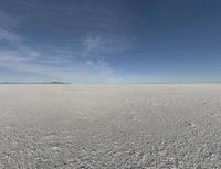 a lone person on a large ice covered field with some desert around it in the background