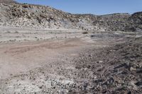 a dirt road in the middle of an empty desert, with hills in the background