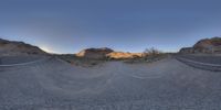 a skateboard ramp in a desert with mountains in the background and a road to the right