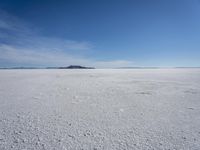 the large expanse of flat snow in the desert under blue skies with mountains in distance