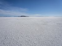 the large expanse of flat snow in the desert under blue skies with mountains in distance