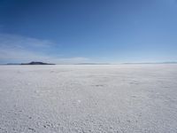 the large expanse of flat snow in the desert under blue skies with mountains in distance