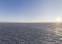 the view of a sun shining through the sky over a vast desert plain with footprints of people