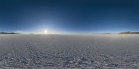 the sun shines above a snow field full of tracks of the skiers in the distance