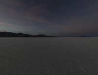 a lone white car traveling on the desert surface during sunset time in the daytime time