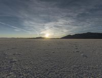 the sun shines in the distance over the vast area where footprints are seen in the snow