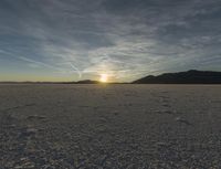 the sun shines in the distance over the vast area where footprints are seen in the snow