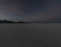 a picture that shows the dark sky above a vast plain of sand and hills at sunset