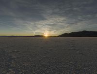 a view of the sun setting over a vast area with some hills in the background