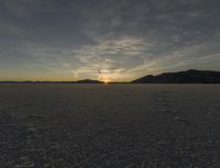 a view of the sun setting over a vast area with some hills in the background