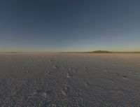 a desert landscape at sunset with an airplane in the sky, on the horizon are mountains and small snow flakes