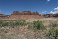 the landscape is filled with tall brown cliffs, trees and shrubbery under a blue sky