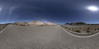 a 360 - lens picture of a deserted road in the desert with no traffic and no people